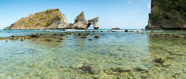 Rock formations on shore against blue sky