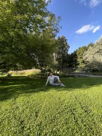 People sitting on field against trees