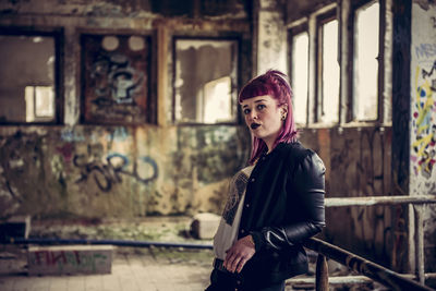 Portrait of woman standing by railing in abandoned building