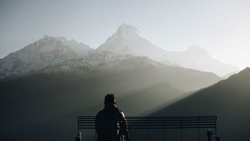 Rear view of man standing on mountain against sky