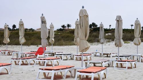 Chairs and tables on beach against clear sky