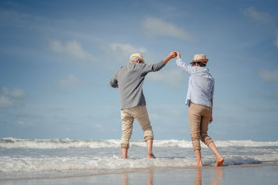 Rear view of people on beach against sky