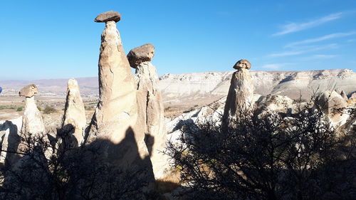 Low angle view of rocks on rock against blue sky
