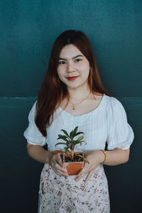 Portrait of smiling young woman standing against black background