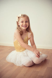 Portrait of cute girl sitting on hardwood floor