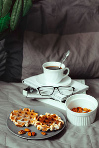 Breakfast in bed - belgian waffles with sauce and a cup of coffee on a wooden tray