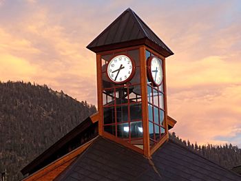 Clock tower by building against sky during sunset