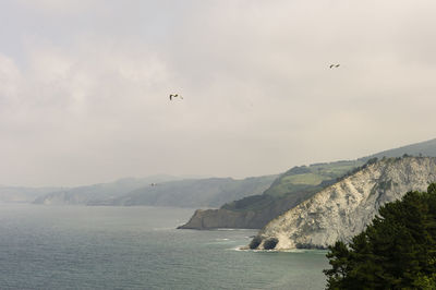 Scenic view of sea and mountains against sky