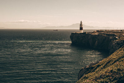 Lighthouse by sea against sky