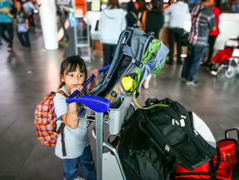 Side view of girl with luggage standing in airport