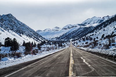 Road amidst snowcapped mountains against sky