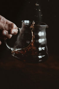 Close-up of hand holding glass jar on table