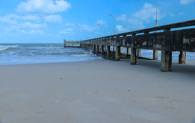 Pier on beach against sky