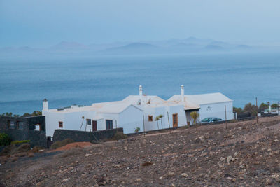 Houses on beach by buildings against sky