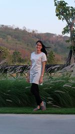 Portrait of smiling young woman standing on landscape against sky