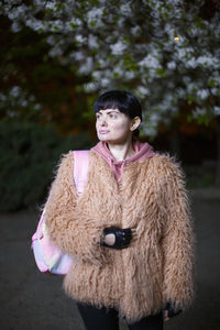 Woman wearing fur coat while looking away outdoors