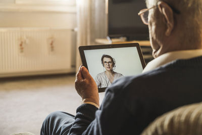 Midsection of man holding mobile phone at home