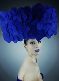 Close-up portrait of woman with headdress against blue background