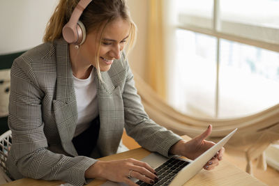 Young woman working at home with laptop on desk and headphones.  notebook for working. 