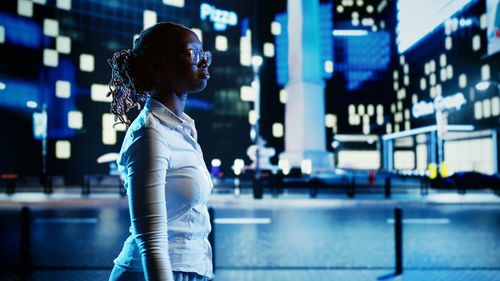 Rear view of woman standing in city at night