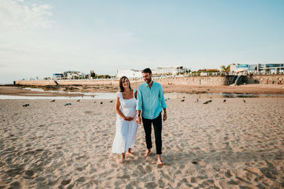 Couple kissing on beach against sky