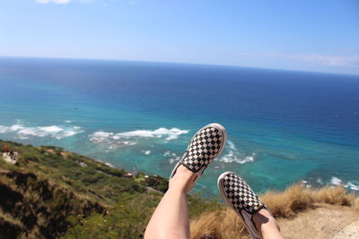 Low section of person with checked pattern shoes against sea