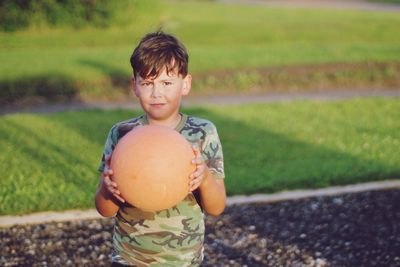 Portrait of boy holding basketball standing outdoors