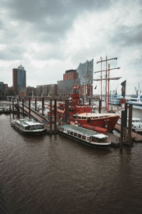 Sailboats moored in harbor against sky in city