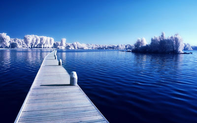 Pier over lake against blue sky