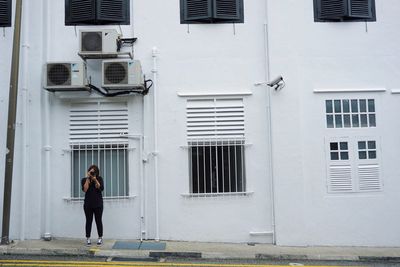 Full length of woman standing against building in city