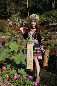 Portrait of a smiling young woman standing against plants