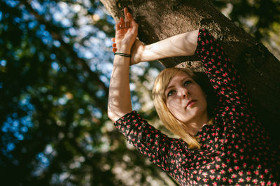 Low angle view of young woman against tree