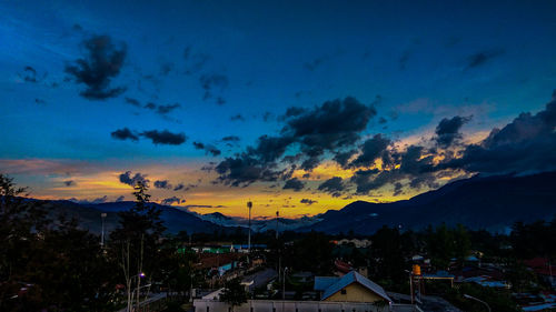 Silhouette houses against sky at sunset