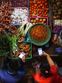 High angle view of man and woman using phone at vegetable shop