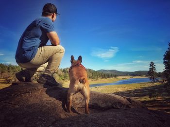 Full length of man with dog against blue sky