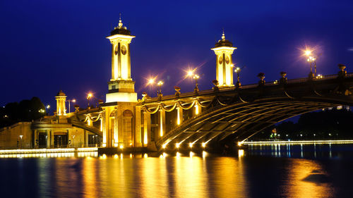 Illuminated bridge over river at night