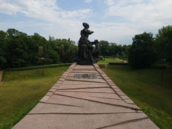 Statue against trees and plants against sky