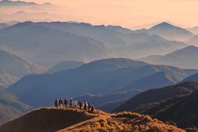 High angle view of people standing on hill against mountain range