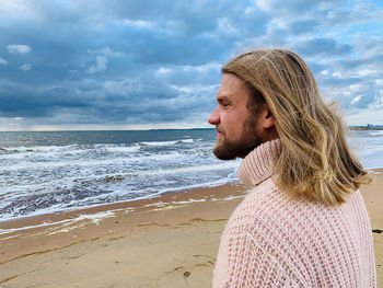 Side view of man on beach against sky