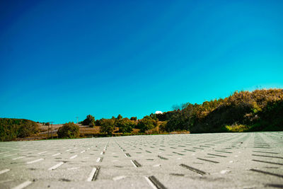 Surface level view of footpath against clear blue sky