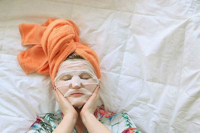 Young woman in orange towel on her head after bath doing self-care procedures at home