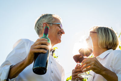 Couple holding wine against sky