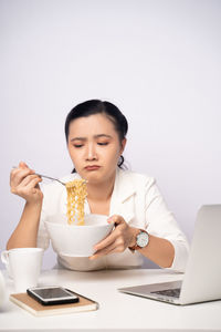 Young woman using mobile phone while sitting on table