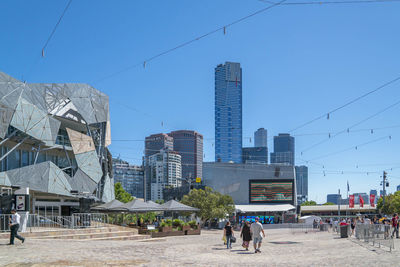 People in city against clear blue sky