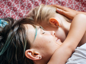 Close-up of smiling mother sleeping with daughter on bed