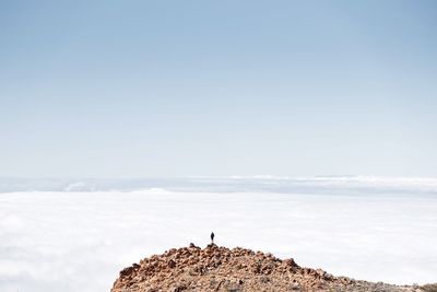 Man standing on rock against sky