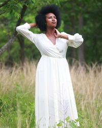 Young woman standing on grass against trees