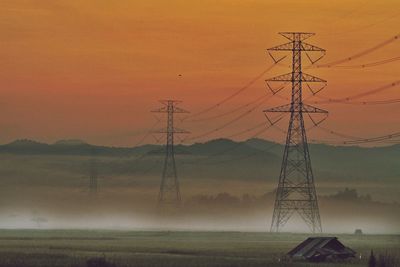 Electricity pylon on field against sky during sunset