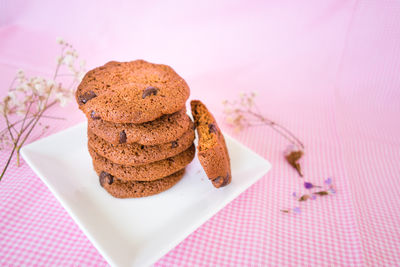 Cropped hand holding cookie against pink background