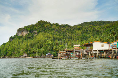 Scenic view of lake and trees by building against sky